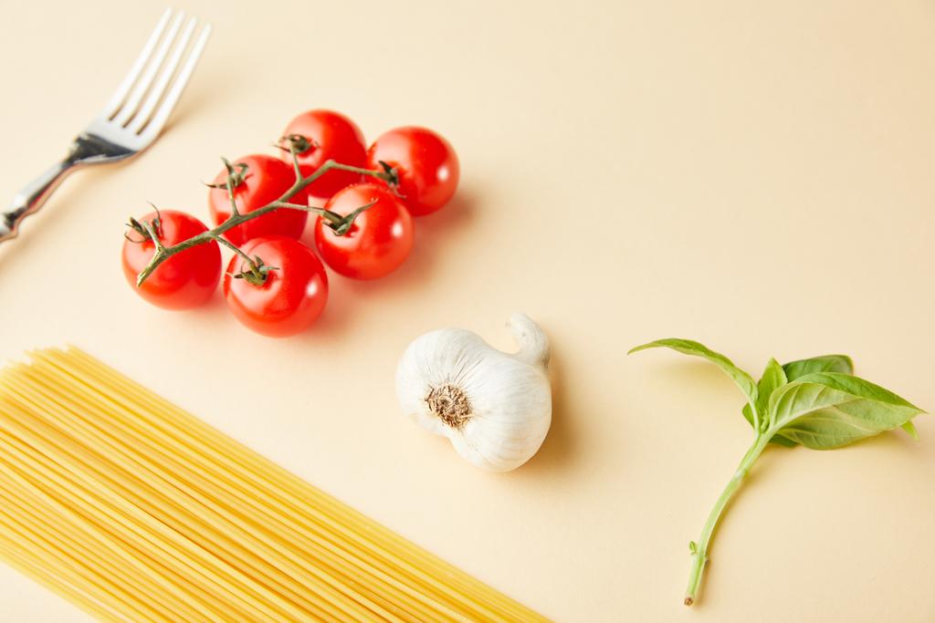 spaghetti crudi, aglio, pomodori, basilico e forchetta su fondo giallo
 - Foto, immagini