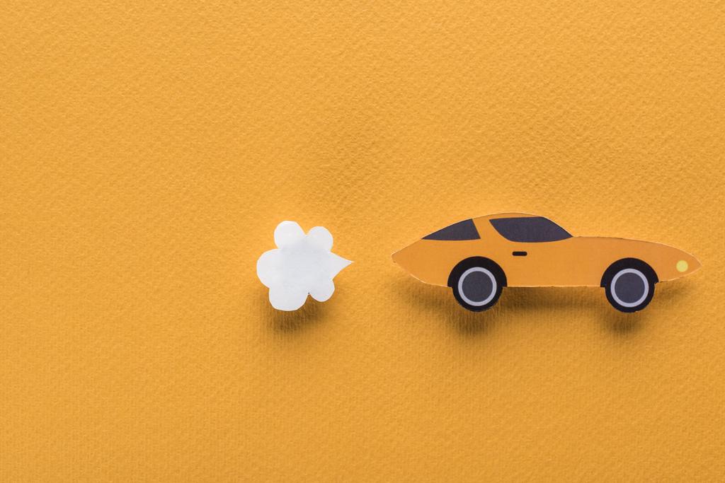 bovenaanzicht van papier gesneden auto op oranje achtergrond met kopieerruimte - Foto, afbeelding