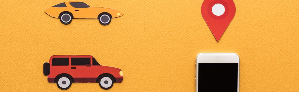 Kağıt kesikli arabaların üst görünümü, akıllı telefonun yanında konum işareti turuncu arka planda boş ekran - Fotoğraf, Görsel