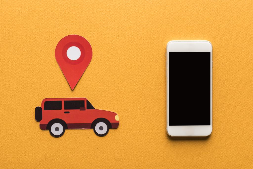 Draufsicht auf Papier geschnittene Autos, Ortsmarke in Smartphone-Nähe mit leerem Bildschirm auf orangefarbenem Hintergrund - Foto, Bild