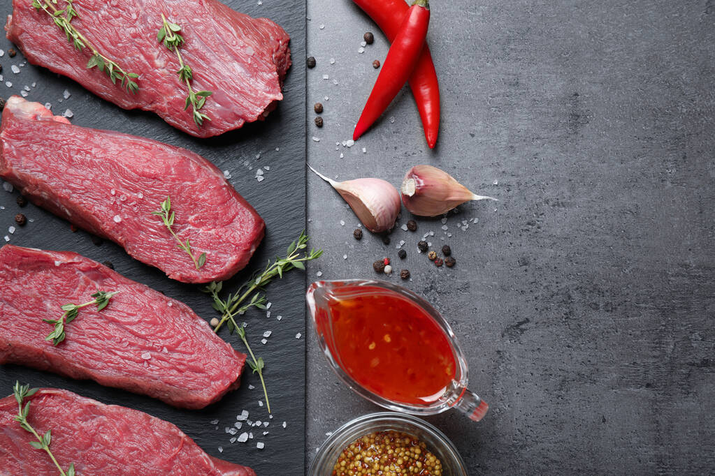 Flat lay composition with fresh meat steaks on grey table - Photo, Image