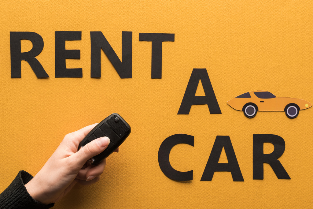 обрезанный вид женщины с ключом рядом с бумагой разрезать аренда автомобиля буквы на оранжевом фоне
 - Фото, изображение