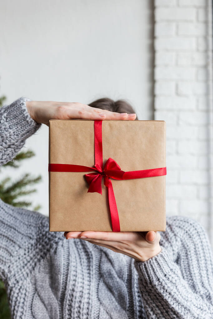 Ambachtelijk papier verpakt doos in hand met kerstboom - Foto, afbeelding