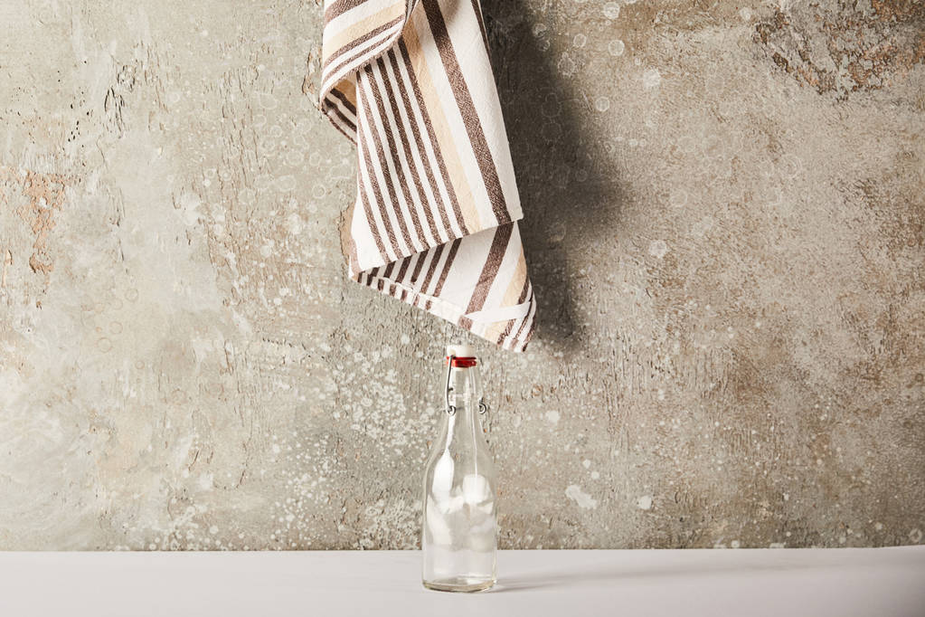 empty glass bottle near striped napkin on stone wall - Photo, Image
