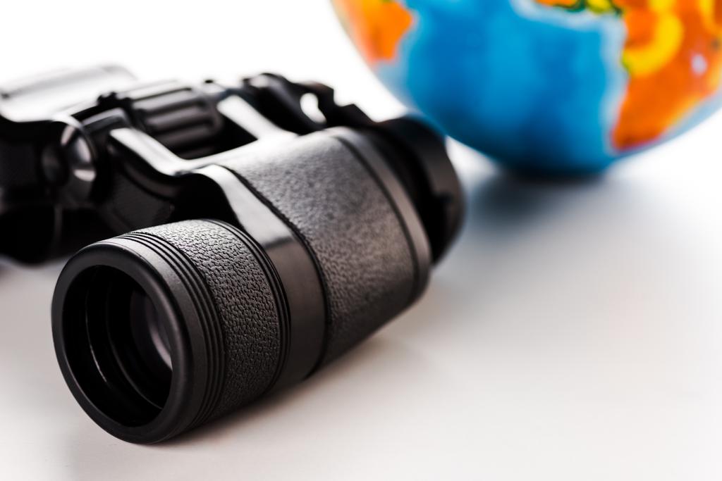 selective focus of binoculars near globe on white  - Photo, Image