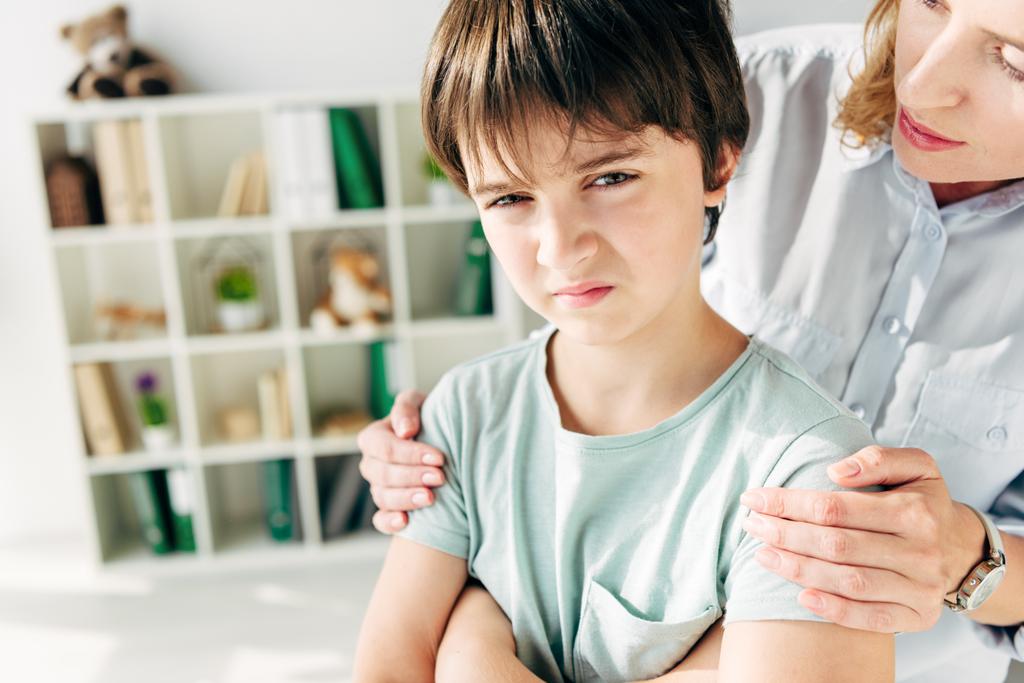 abgeschnittene Ansicht eines Kinderpsychologen, der Kind mit Legasthenie umarmt  - Foto, Bild