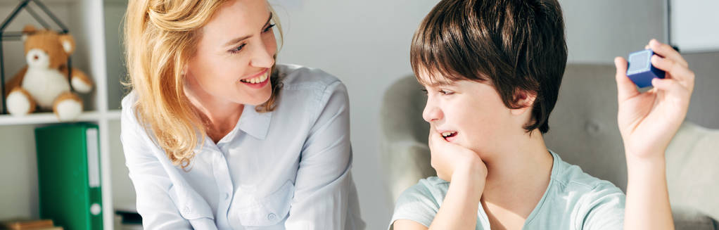 plano panorámico de un psicólogo infantil sonriente mirando a un niño con dislexia
  - Foto, Imagen