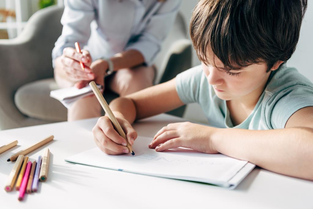 selective focus of kid with dyslexia drawing on paper with pencil  - Photo, Image