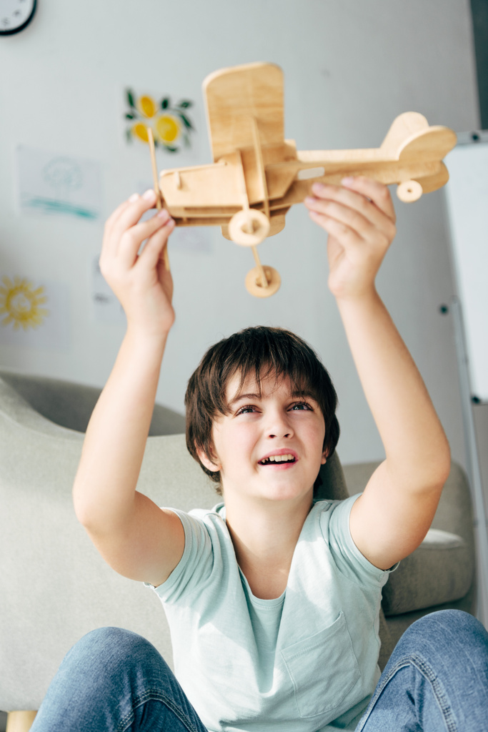 roztomilý kluk s dyslexií hrát s dřevěným letadlem  - Fotografie, Obrázek