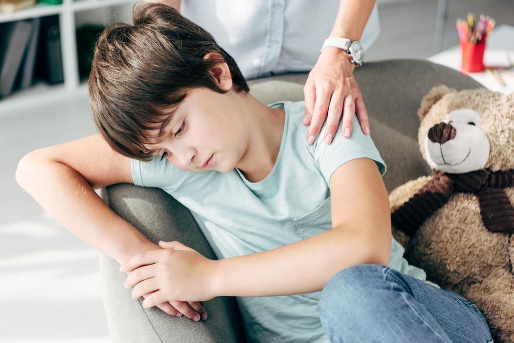 ostříhaný pohled na dětského psychologa objímající smutné dítě s dyslexií  - Fotografie, Obrázek