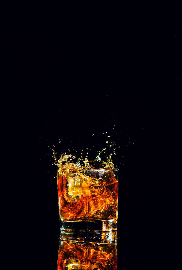 Odizolowany kieliszek whisky z pluskiem na czarnym tle - Zdjęcie, obraz