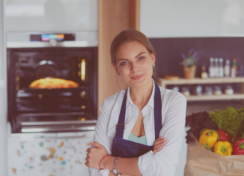 Portrait de jeune femme debout avec les bras croisés sur fond de cuisine - Photo, image