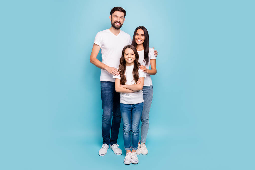 Pełna długość zdjęcie idylliczne mama tata i potomstwo z brunet włosów przytulić cieszyć nosić biały t-shirt dżinsy trampki casual strój izolowany na niebieskim tle - Zdjęcie, obraz