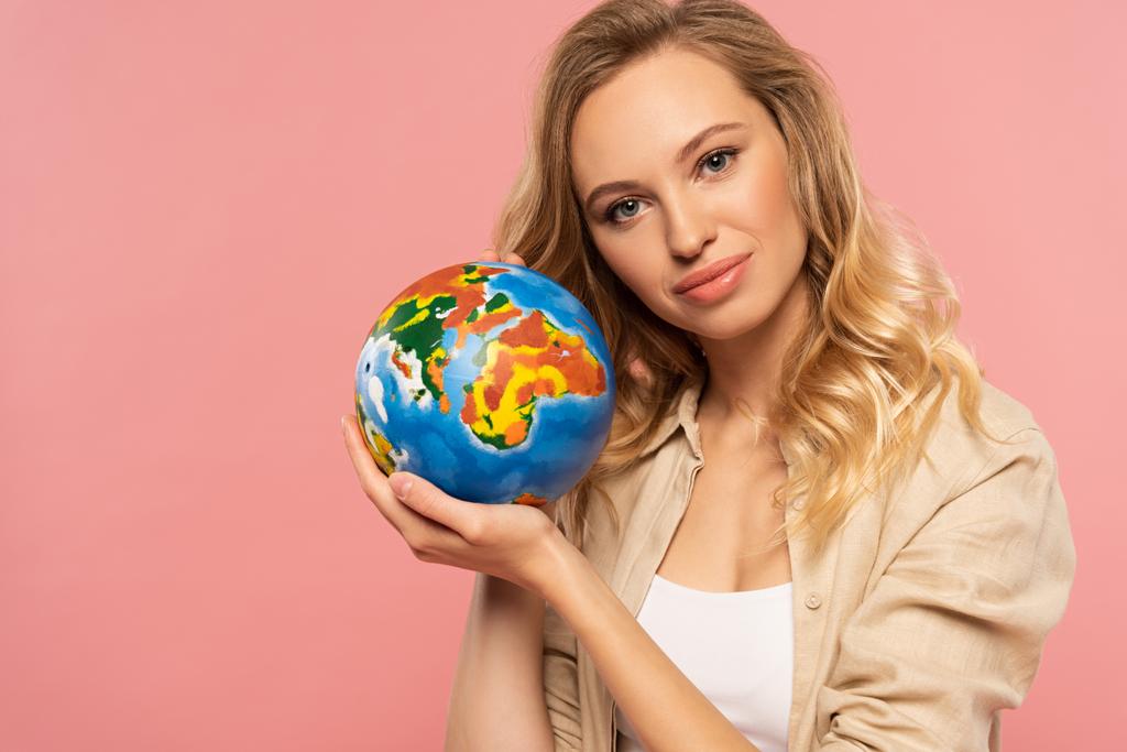Hymyilevä blondi nainen tilalla maapallo eristetty vaaleanpunainen
 - Valokuva, kuva