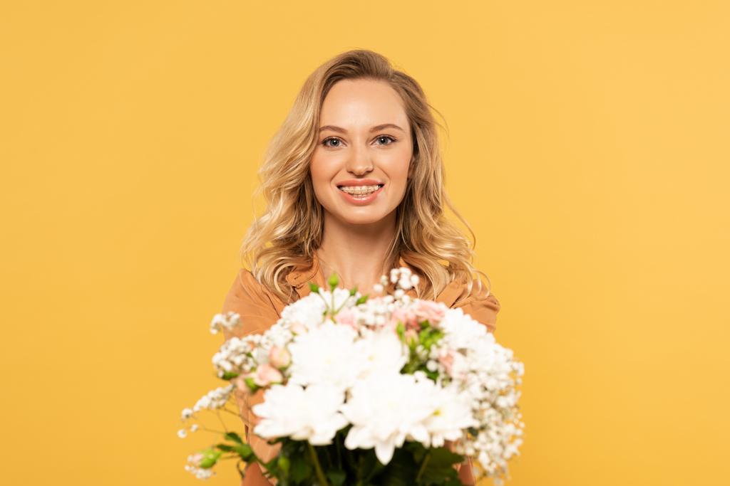 Femme blonde souriante tenant bouquet isolé sur jaune
 - Photo, image