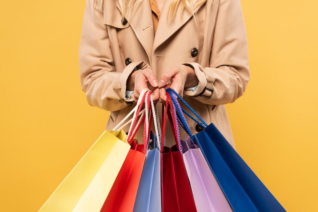 Vista cortada da mulher segurando sacos de compras isolados no amarelo
 - Foto, Imagem