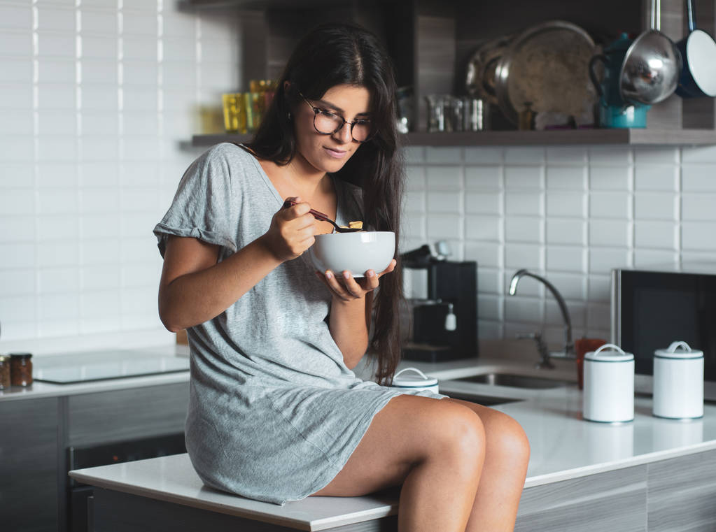 молода жінка снідає на кухні
 - Фото, зображення