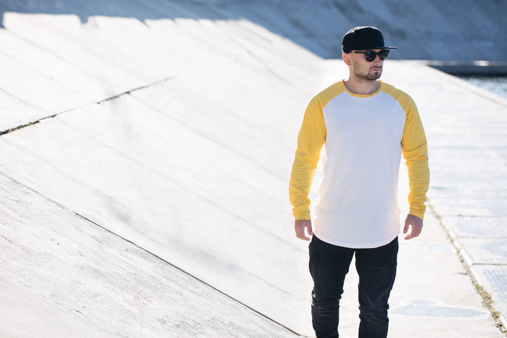 Modelo hombre con barba en blanco y amarillo en blanco Camisa de manga larga para maqueta y gorra de béisbol con espacio para tu logo o diseño en estilo urbano casual
 - Foto, imagen