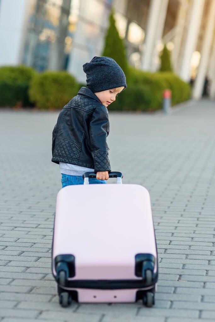 Linda chica viajera tira de la maleta rosa hacia el aeropuerto
. - Foto, imagen