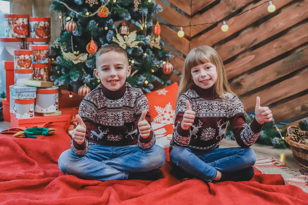 Kaukázusi testvérek viselnek bordó gyapjú pulóverek mutatják hüvelykujj fel, elégedett újévi hangulat. - Fotó, kép