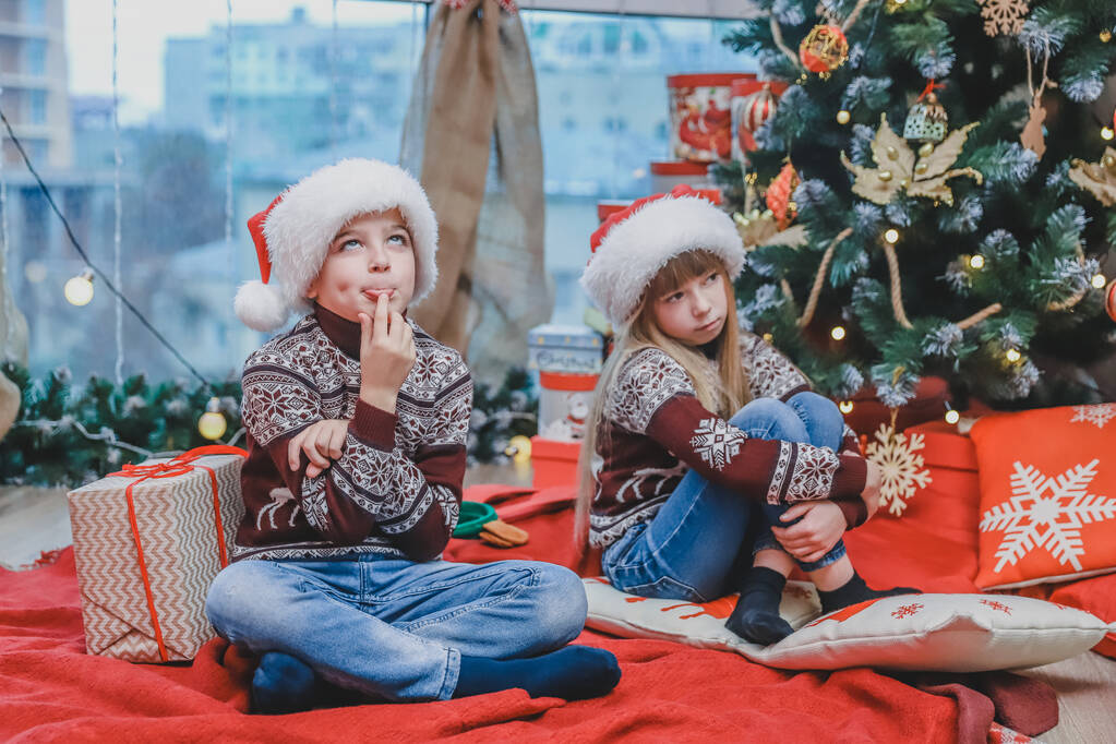 クリスマスの夜に心を持った子供たちの写真彼らがプレゼントとして何を得るか疑問に思う. - 写真・画像