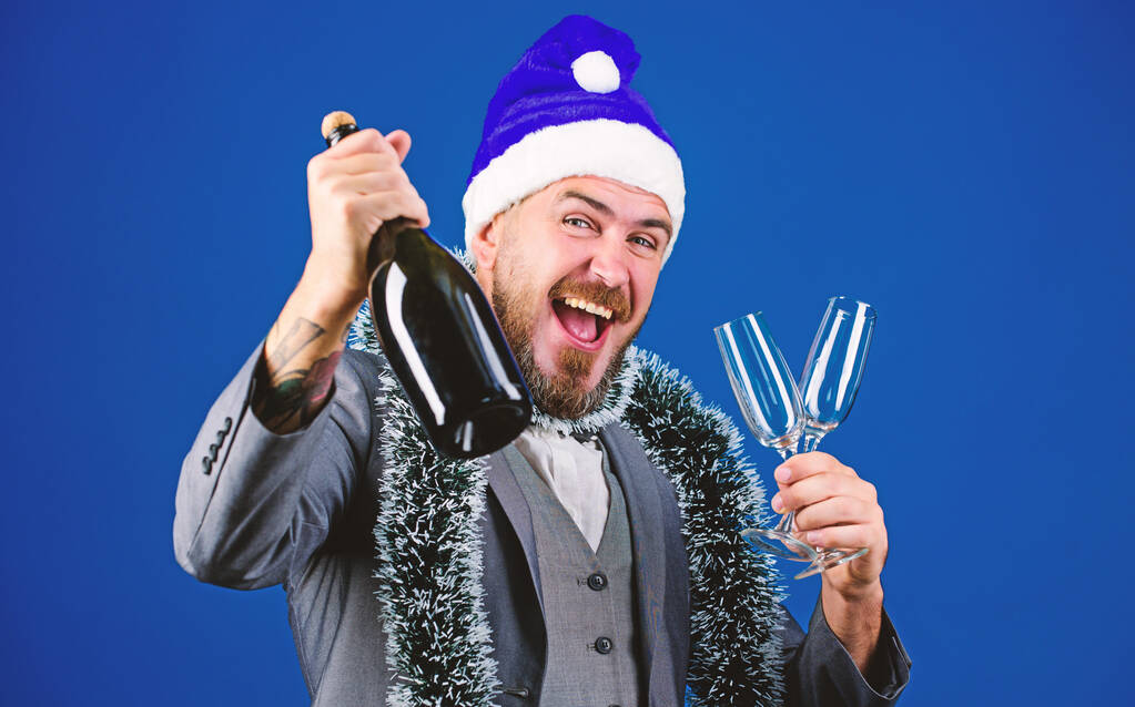 Ідеї корпоративних вечірок сподобаються співробітникам. Корпоративна різдвяна вечірка. Чоловік бородатий веселий хіпстер Санта тримає шампанське і окуляри. Організатори різдвяної вечірки. Бос мішура готова відсвяткувати новий рік
 - Фото, зображення