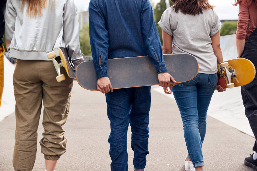 Rückansicht von Freundinnen mit Skateboards, die durch den städtischen Skatepark laufen - Foto, Bild