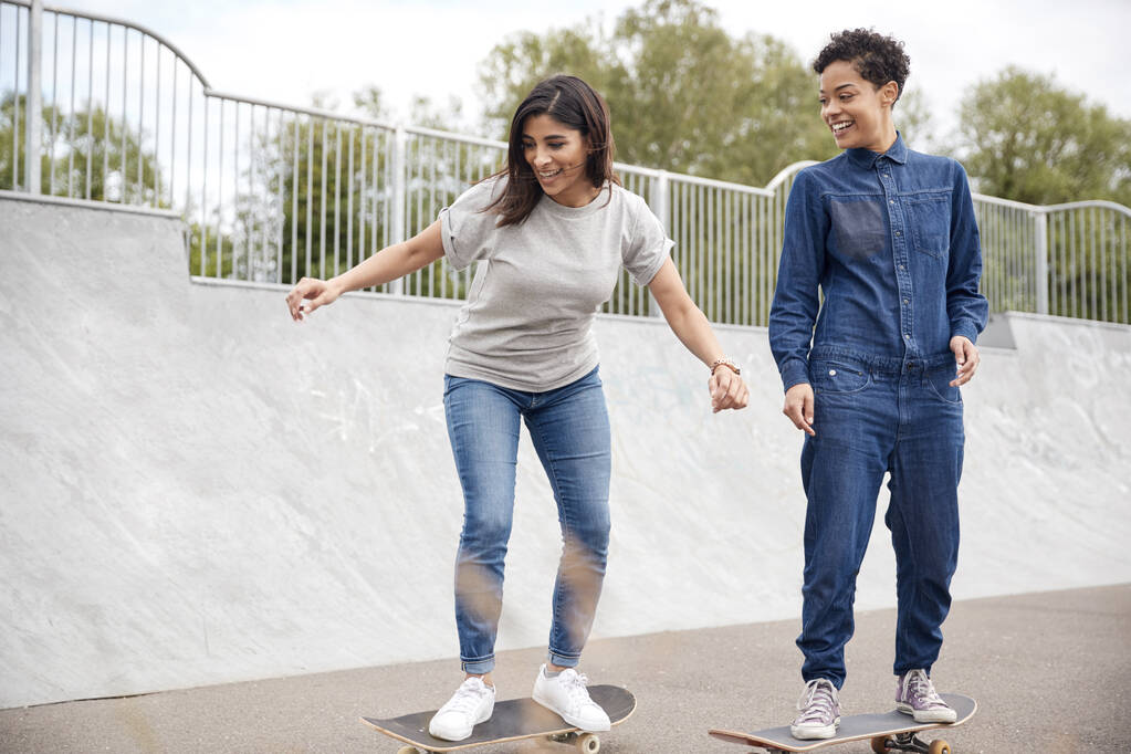 Two Female Friends Riding On Skateboards In Urban Skate Park - Photo, Image