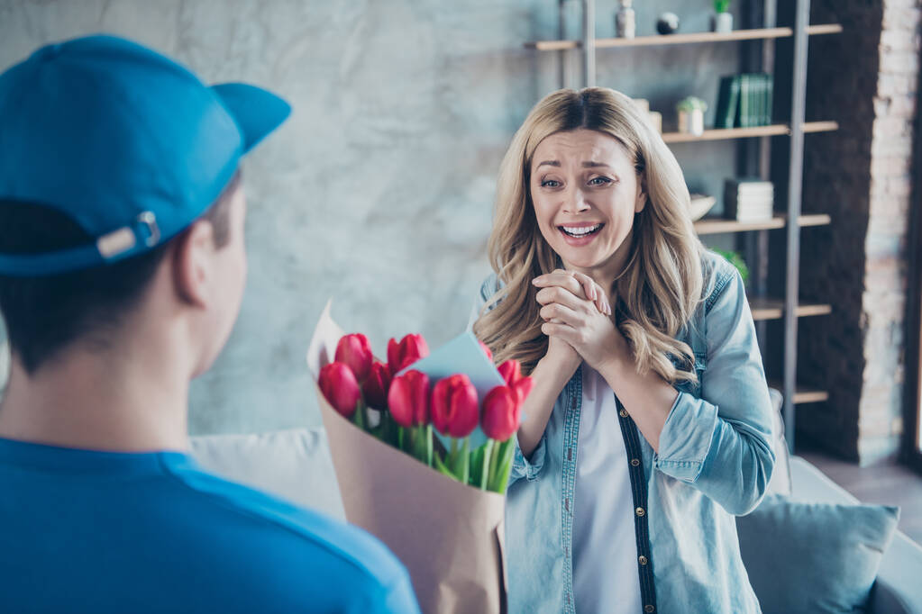 Portrait of nice attractive lovely charming pretty glad pleased cheerful cheery wavy-haired girl getting receiving greetings red flowers at modern industrial loft brick style interior living-room - Photo, Image