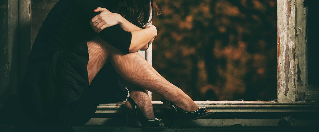 Frau mit schönen Beinen in Schuhen sitzt auf einem alten Fenster - Foto, Bild