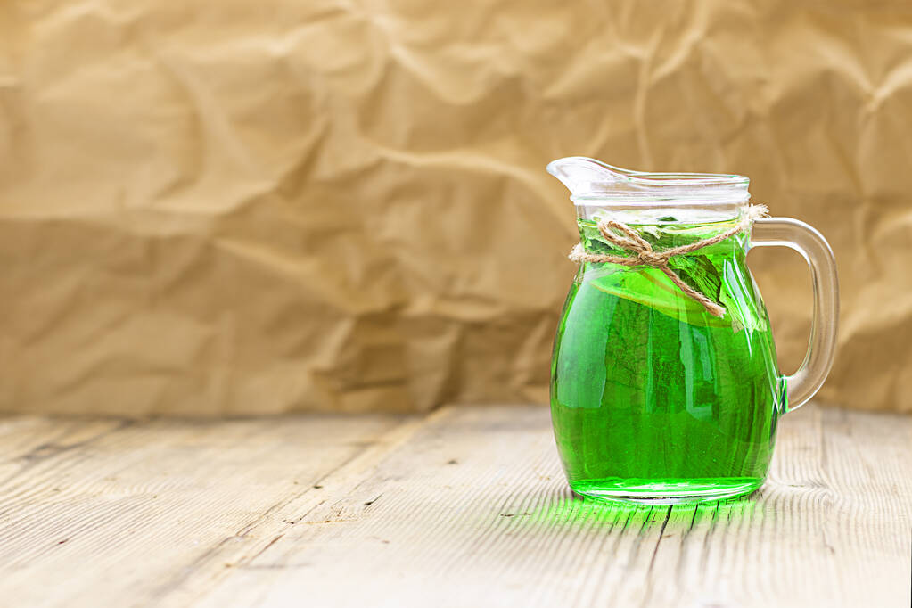 Sommer kaltes grünes Getränk aus Estragon, mit Minze und Zitronenscheiben im Glasdekanter. horizontal mit Kopierraum. Estragon Schaumgetränk. Limonade - Foto, Bild