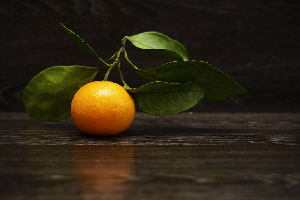 Свежий, спелый мандарин с листьями на поверхности черного камня
. - Фото, изображение