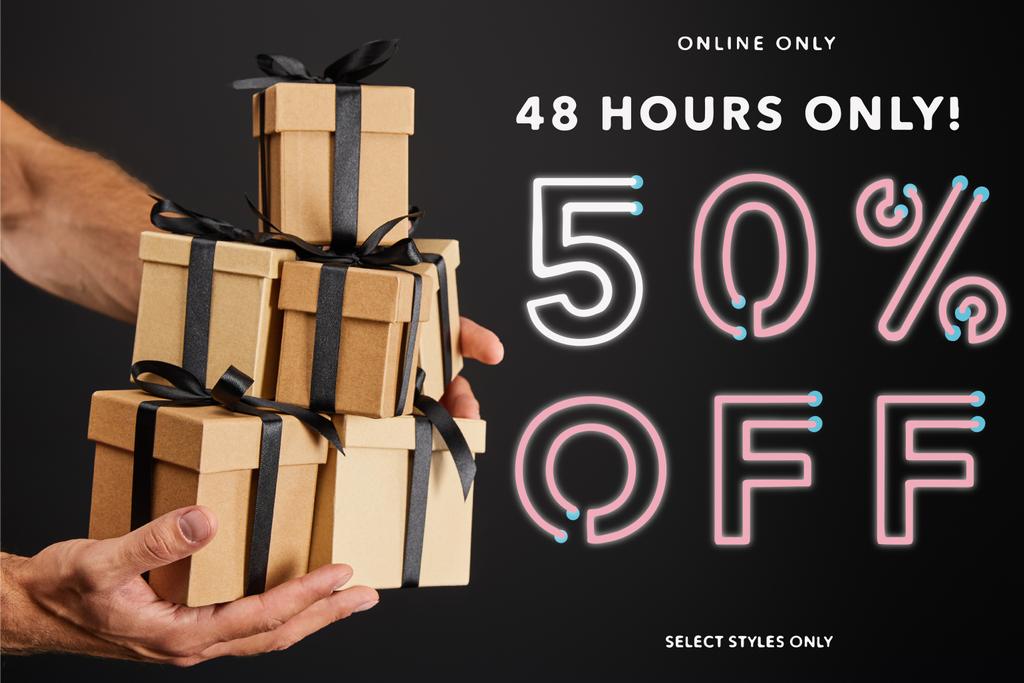 обрезанный вид человека, держащего картонные подарочные коробки с лентами изолированы на черном с 48 часов 50 процентов от иллюстрации, черная пятница концепции
 - Фото, изображение