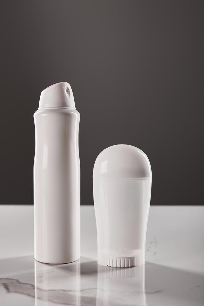 котити і розбризкувати пляшки дезодоранту на мармуровому столі ізольовані на сірому
 - Фото, зображення