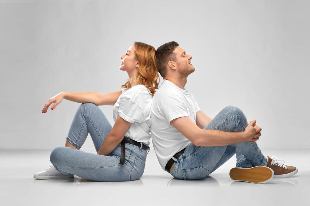 happy couple in white t-shirts sitting on floor - Photo, Image
