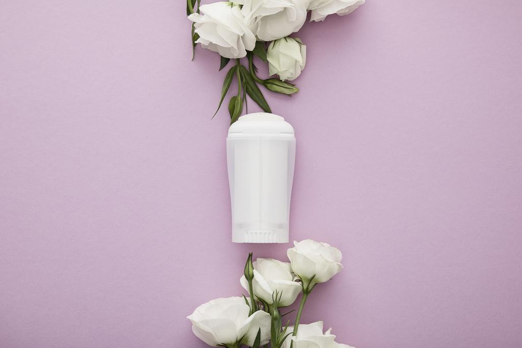 Beyaz güllü, menekşe arkaplanındaki deodorant şişesinin en üst görüntüsü - Fotoğraf, Görsel