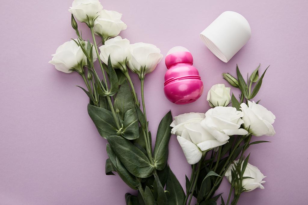 felső nézet tekercs üveg dezodor lila háttér fehér rózsa - Fotó, kép