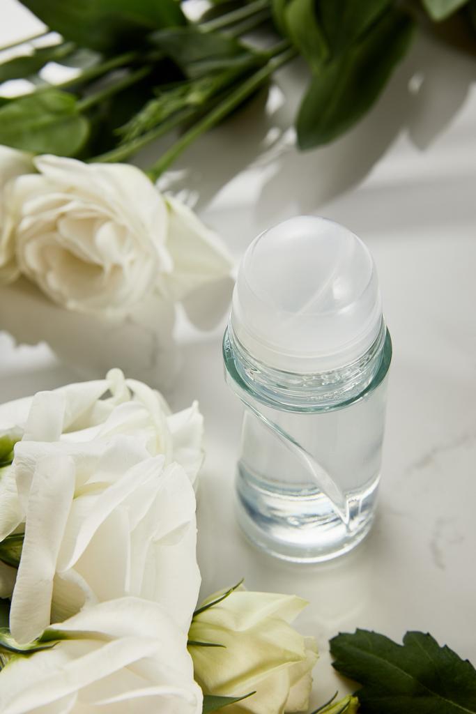role na lahvičce deodorantu s růžemi na bílém povrchu - Fotografie, Obrázek