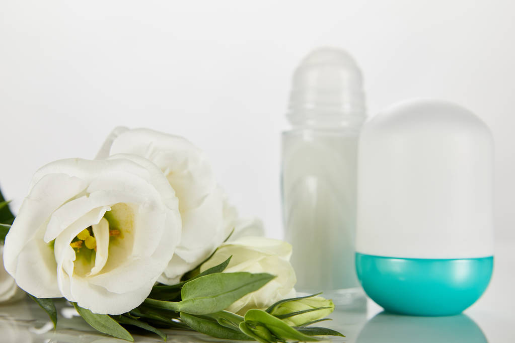 selective focus of roll on bottles of deodorant with roses isolated on white - Photo, Image