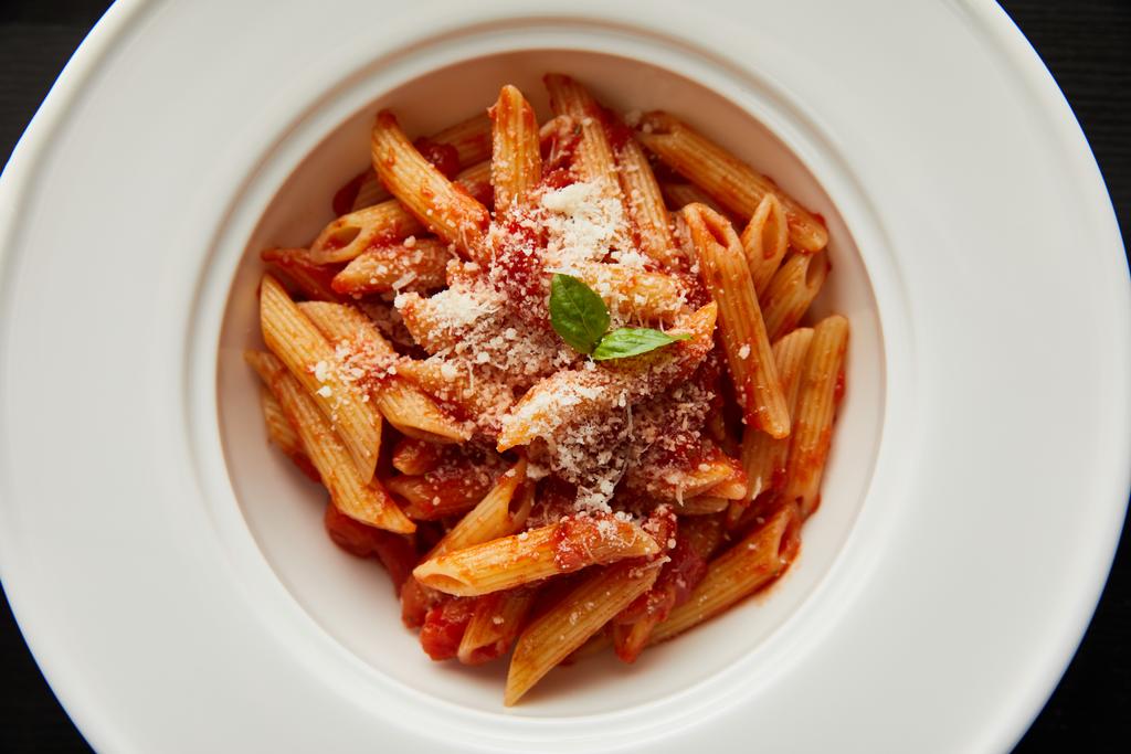 vista dall'alto gustosa pasta bolognese con sugo di pomodoro e parmigiano in piatto bianco isolato su nero
 - Foto, immagini