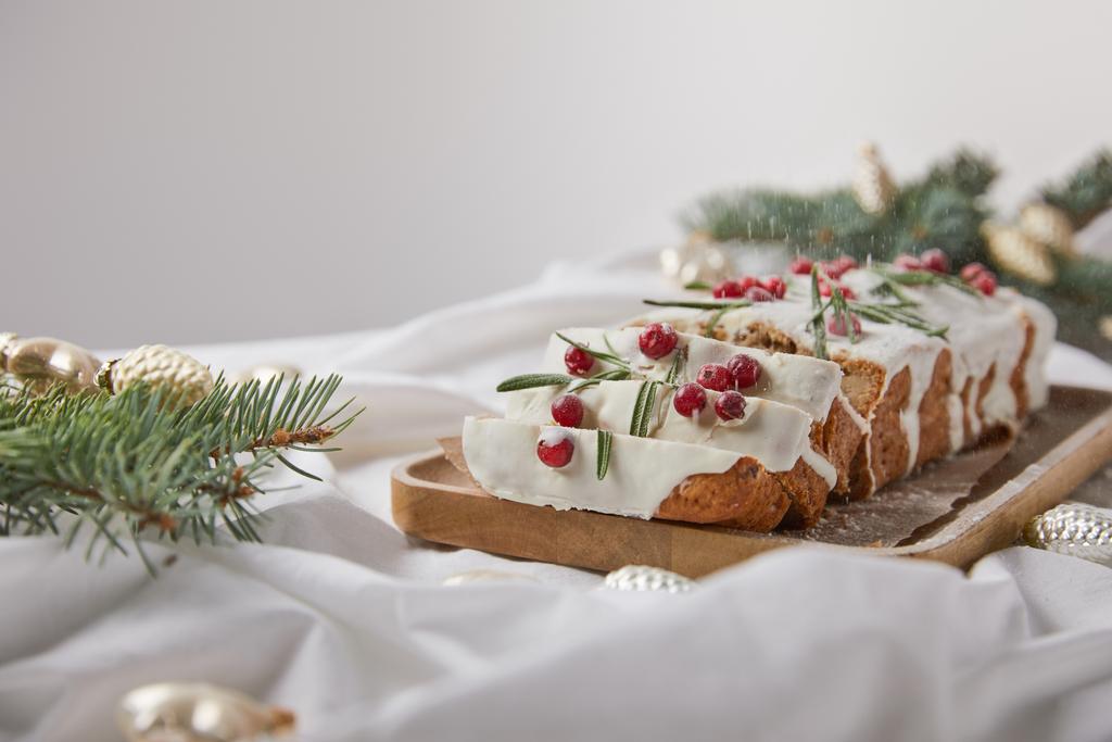 selektiver Schwerpunkt des traditionellen Weihnachtskuchens mit Preiselbeere auf Holzbrett in der Nähe von Silberkugeln und Tannennadeln isoliert auf grau - Foto, Bild