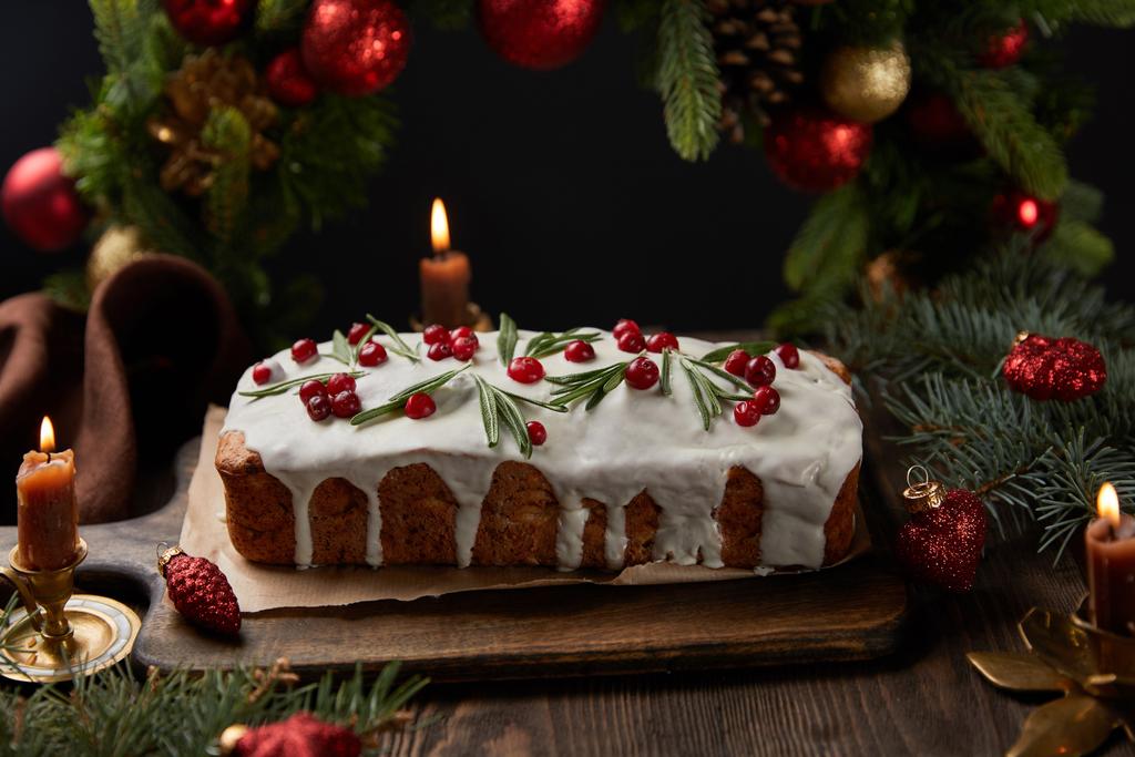 hagyományos karácsonyi torta áfonyával közel karácsonyi koszorú baubles és gyertyák fa asztalon elszigetelt fekete - Fotó, kép