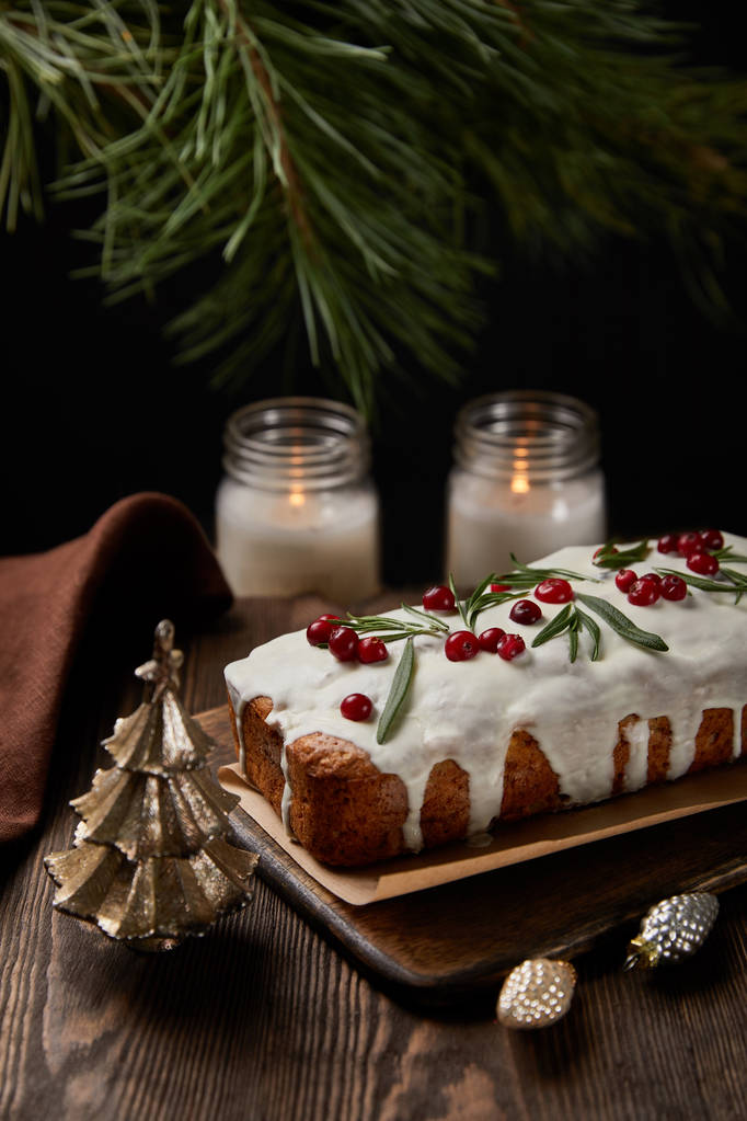 pastel tradicional de Navidad con arándano cerca de pino, bolas y velas en la mesa de madera
 - Foto, imagen