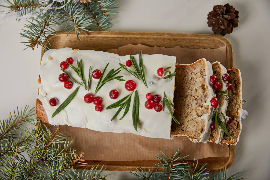 vista superior del pastel tradicional de Navidad con arándano cerca de pino y cono en la mesa blanca
 - Foto, imagen