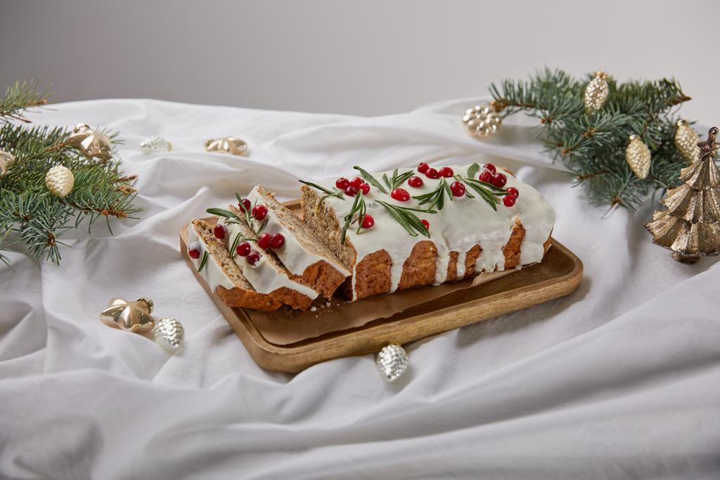 traditional Christmas cake with cranberry on wooden board near silver baubles and pine isolated on grey - Photo, Image