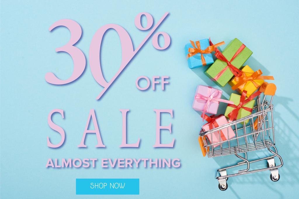 bovenaanzicht van feestelijke ingepakte cadeautjes in winkelwagen op blauwe achtergrond met 30 procent korting op verkoop illustratie - Foto, afbeelding