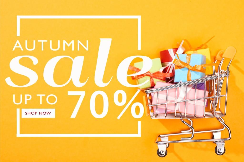 vista superior do carrinho de compras com presentes em fundo laranja brilhante com venda de outono, até 70 por cento ilustração
  - Foto, Imagem