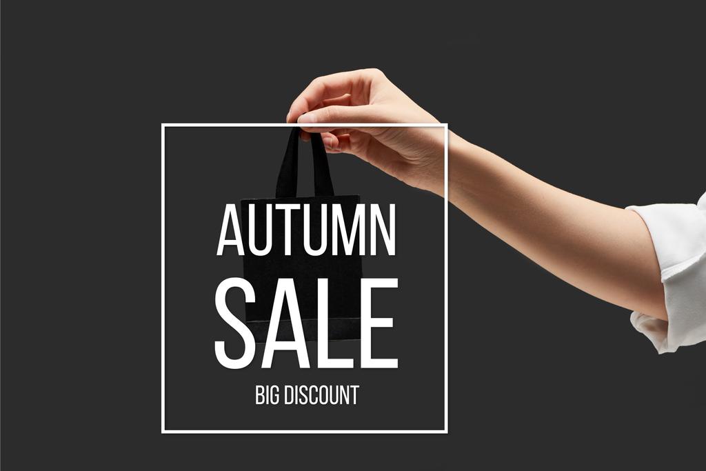 vista recortada de la mujer sosteniendo pequeño bolso de compras negro en mano aislado en negro con ilustración de venta de otoño
  - Foto, imagen