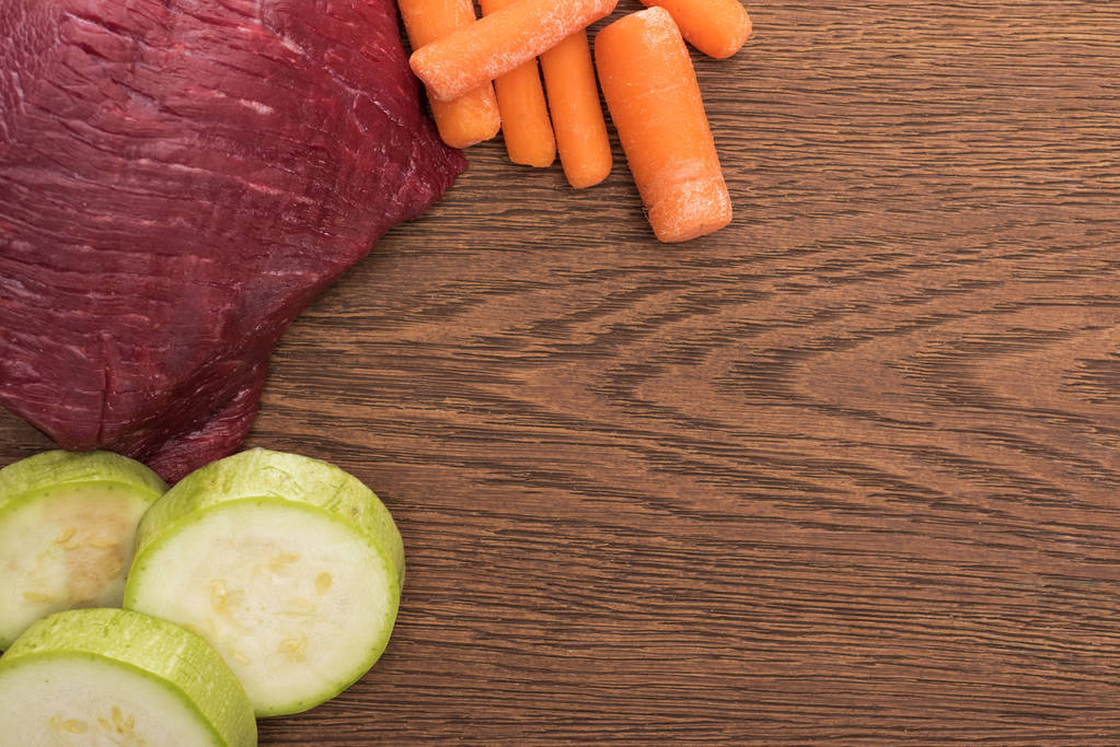 Draufsicht auf rohes Fleisch, Zucchini und Karotte auf Holztisch - Foto, Bild