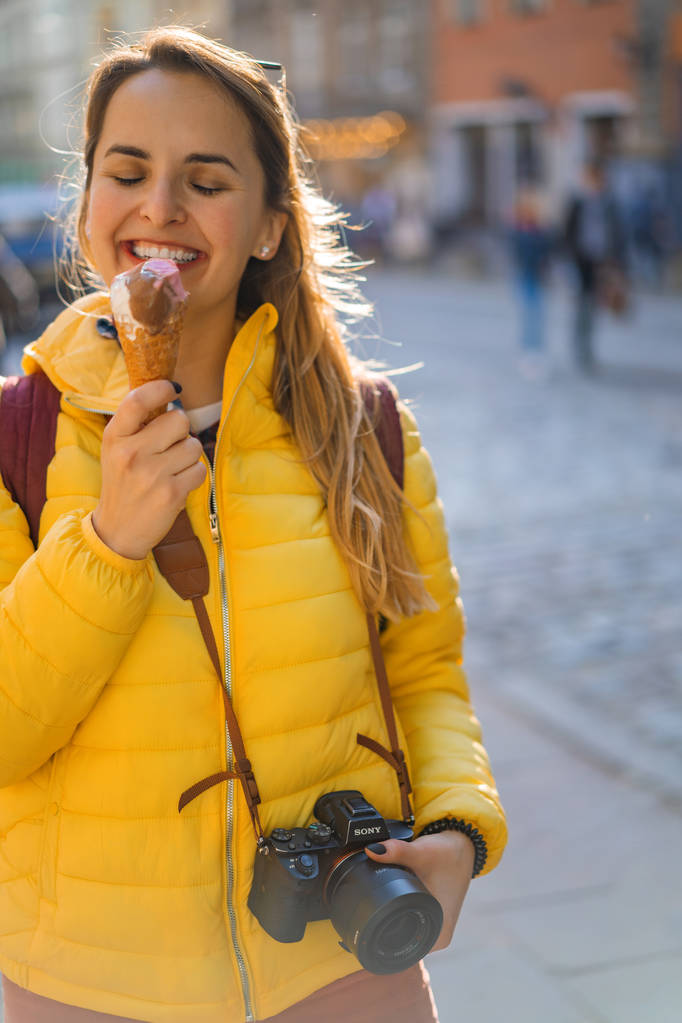 jonge vrouw toerist, eten ijs, gelukkig, lachen, heldere zonnige dag, toeristische camera. - Foto, afbeelding
